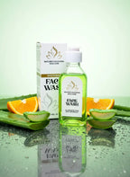 Face wash bottle with packaging on a reflective surface with fruits and aloe vera leaves.